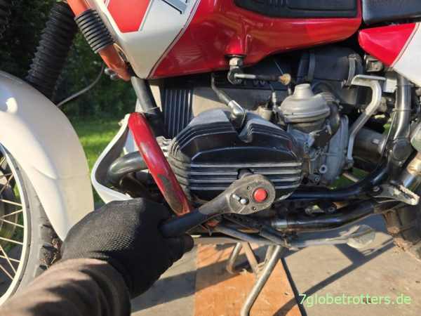 Lösen der zentralen Hutmutter mittig auf der Zylinderkopfhaube Lösen der zentralen Hutmutter mittig auf der Zylinderkopfhaube